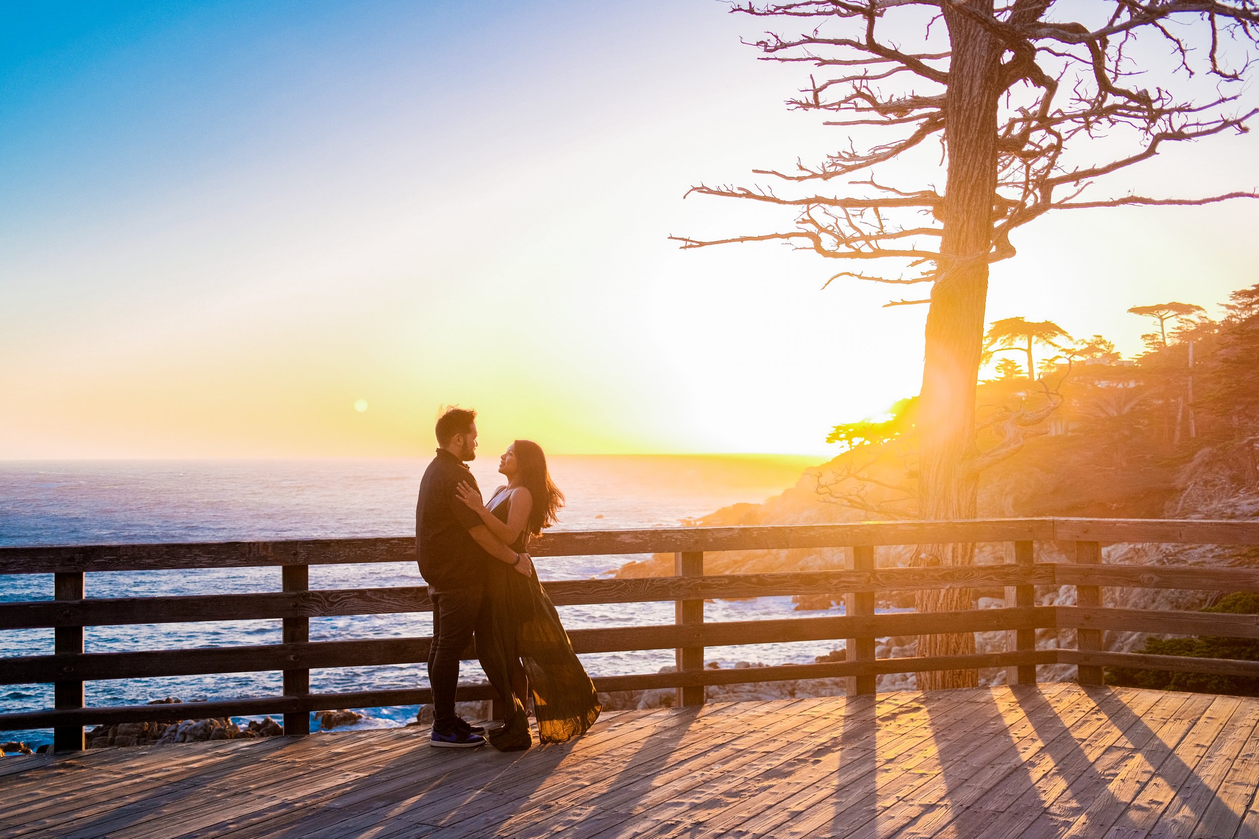 Couple posing during a destination photoshoot with a beautiful sunset in the background, capturing the golden hues of the setting sun.